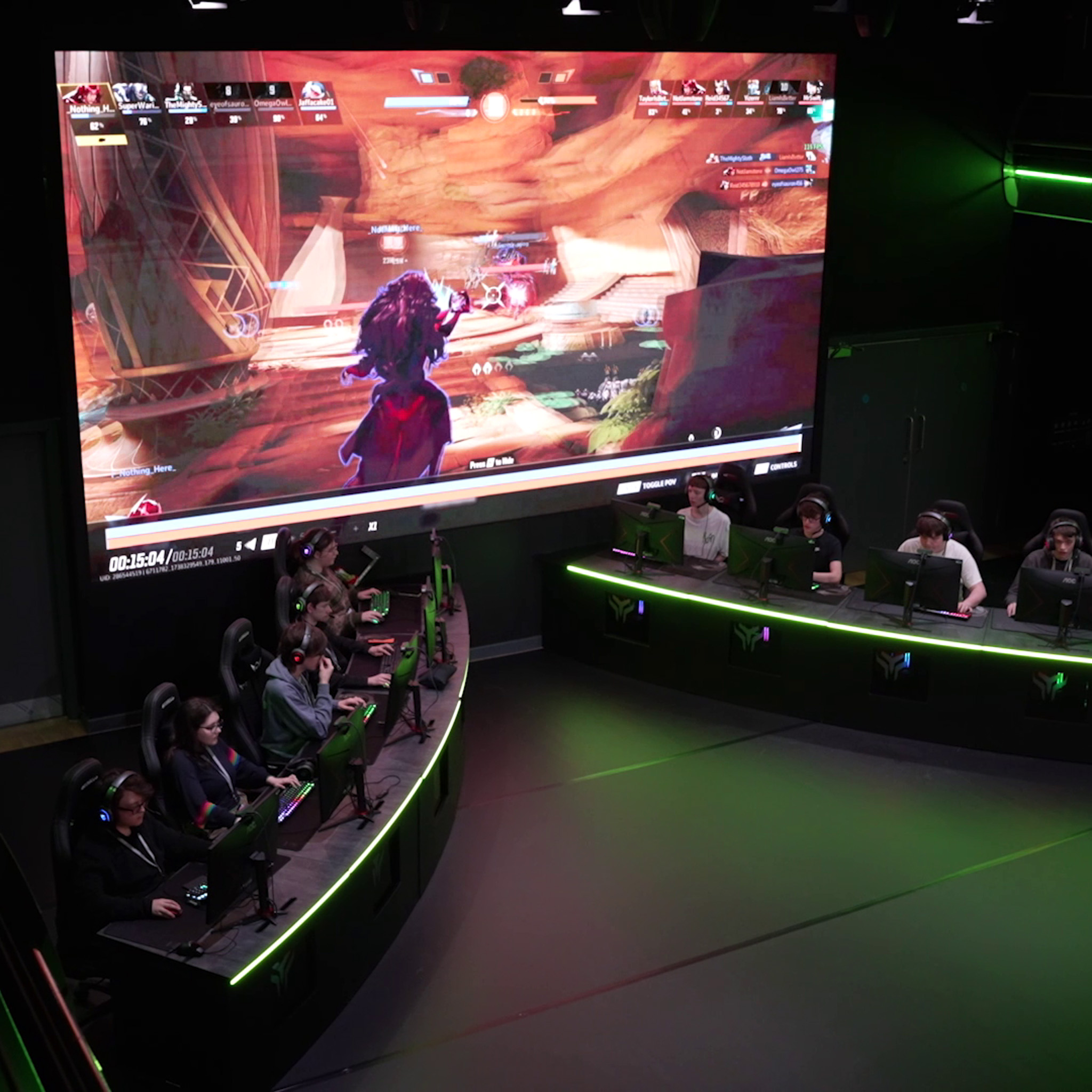 A professional esports arena stage setup with a large projection screen and team desks for competitive student gaming
