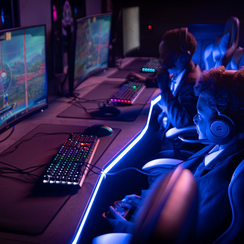 Two students at a desk holding controlers playing rocket league at Mary Immacualte esports education suite.