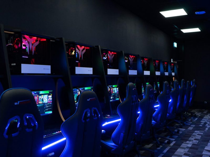 Fully installed school esports arena design by Yoyotech, featuring a row of custom gaming PCs and ergonomic furniture with blue LED lighting.